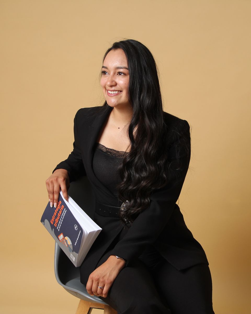 María Paula Medina sentada con un libro de estrategia tributaria
